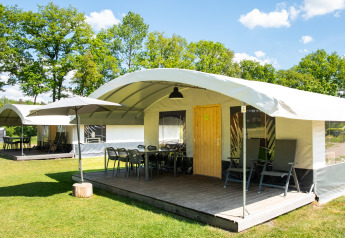 Tienda safari llamada Tentvilla en el parque De Witte Berg, Países Bajos, con terraza y mobiliario exterior.
