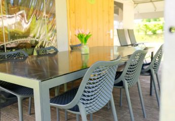 Outdoor dining table with stylish chairs and a vase of flowers at Tentvilla safari tent, De Witte Berg, Netherlands.
