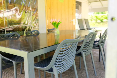 Mesa de comedor exterior con sillas modernas y jarrón de flores en la Tentvilla del parque De Witte Berg.