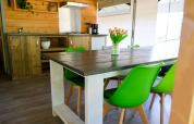 Eethoek met groene stoelen en houten keuken in de Tentvilla safaritent bij De Witte Berg, Nederland.