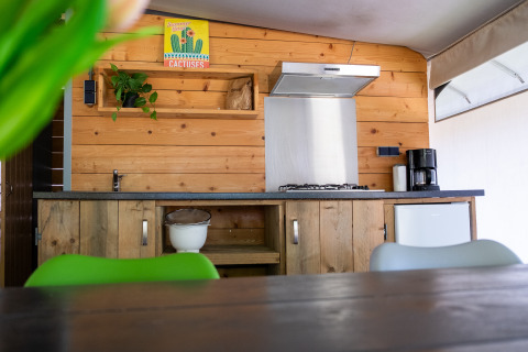 Coin cuisine moderne dans une tente safari à De Witte Berg avec murs en bois, cafetière et décoration verte.