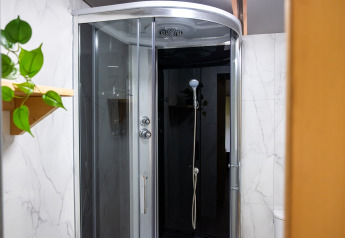 Moderne douchecabine met glazen deuren en zwarte wand in de badkamer van Tentvilla bij De Witte Berg.