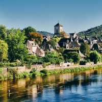 Vista pittoresca di un borgo fluviale con chiesa e case tradizionali vicino a Saint-Astier, Nuova Aquitania.