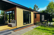 Sunlodge en Holiday Park 't Rheezerwold, Países Bajos, moderno albergue de madera con terraza y jardín.