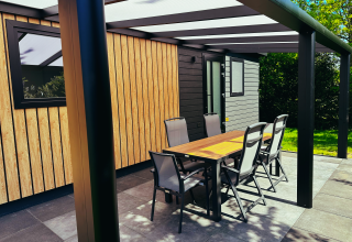 Buitenterras van Sunlodge bij Holiday Park 't Rheezerwold, Nederland, met tafel en zes stoelen.
