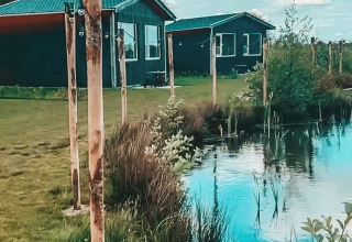 Cottage, luci decorative e laghetto tranquillo nel parco vacanze The Kremmer a Drenthe, Paesi Bassi.