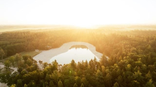 Luchtfoto van een meer omgeven door bos bij zonsondergang in vakantiepark De Kremmer, Drenthe, Nederland.