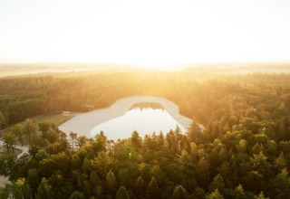 Vue aérienne d’un lac entouré de forêt au coucher du soleil dans le parc de vacances The Kremmer, Drenthe, Pays-Bas.
