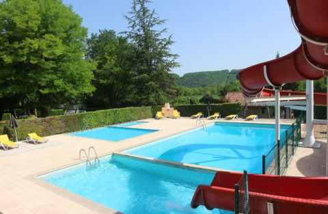 Outdoor pool with waterslide, loungers, and lush greenery at Camping Le Céou in Nouvelle-Aquitaine, France.