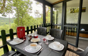 Outdoor breakfast table set for four on a glamping terrace overlooking forest and countryside.