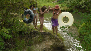 Kinderen in badkledij met zwembanden trekken naar de rivier bij Camping Le Céou in Nouvelle-Aquitaine, Frankrijk.