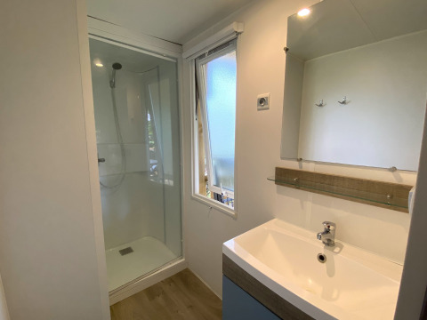 Bagno moderno nella Stacaravan al Camping Le Céou, Francia, con doccia, lavandino e specchio.
