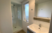 Modernes Badezimmer in der Stacaravan auf Camping Le Céou, Frankreich, mit Dusche und Waschbecken.