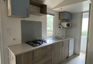 Moderne keuken in een Stacaravan bij Camping Le Céou in Frankrijk met kookplaat, gootsteen en koelkast.