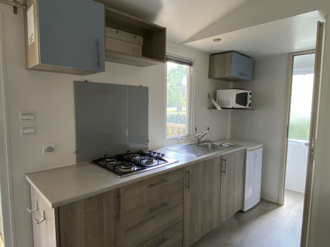 Moderne keuken in een Stacaravan op Camping Le Céou in Frankrijk met fornuis, gootsteen en magnetron.