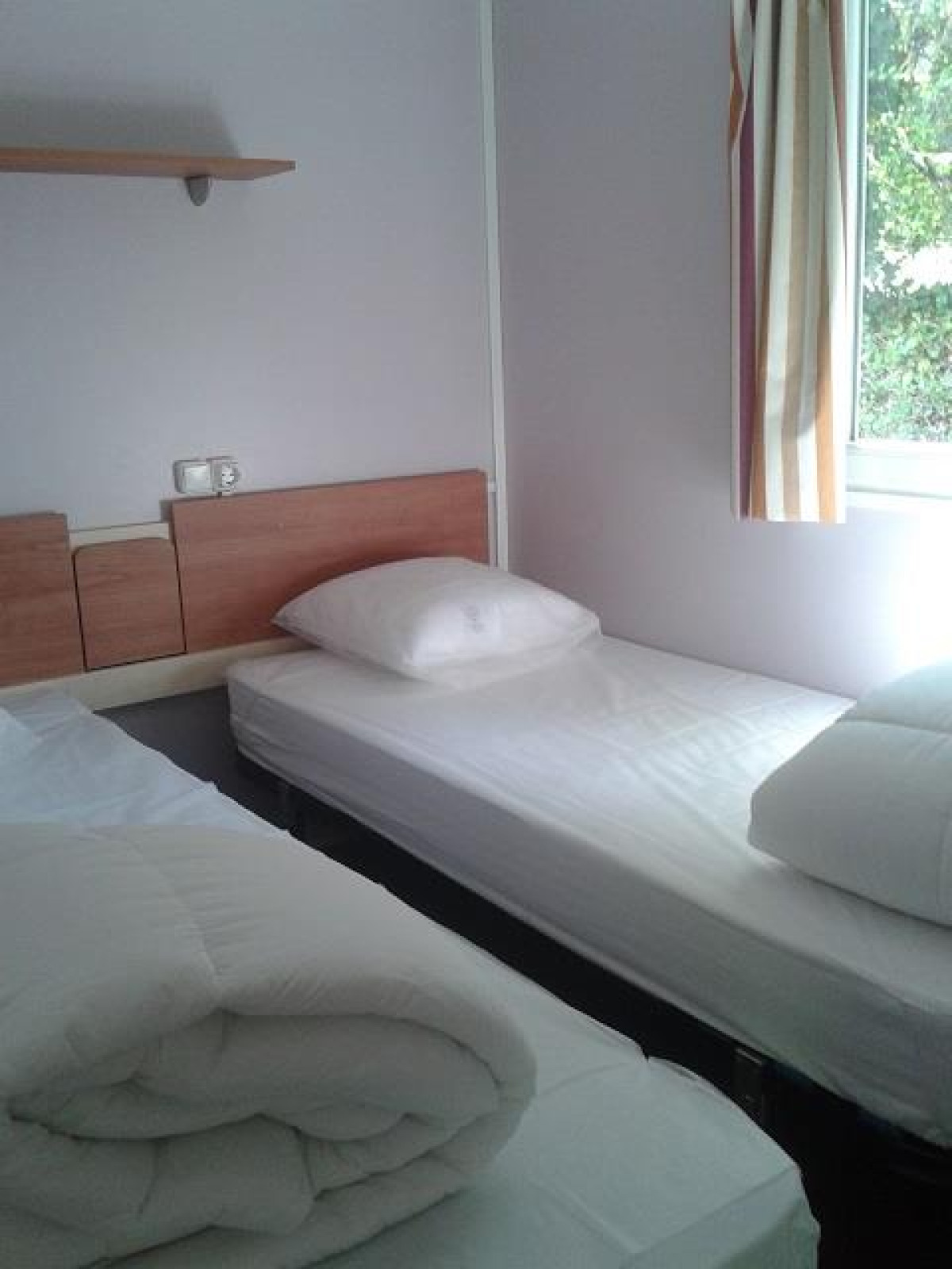 Een foto van een slaapkamer in een hut met twee eenpersoonsbedden bij Stacaravan met airco, Camping Le Céou, Frankrijk.
