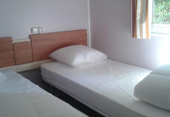 Foto di una camera in una cabina con due letti singoli allo Stacaravan met airco, Camping Le Céou, Francia.