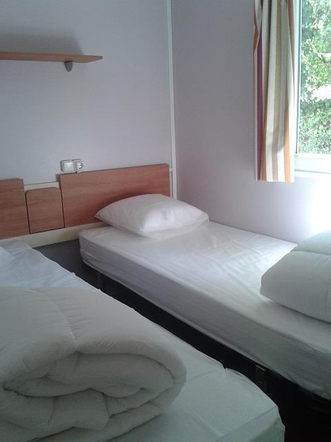 Foto di una camera in una cabina con due letti singoli allo Stacaravan met airco, Camping Le Céou, Francia.