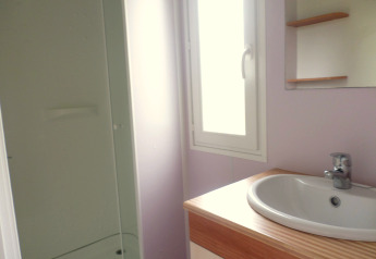 Bright bathroom in Stacaravan met airco at Camping Le Céou, France, featuring a sink, mirror, and shower.