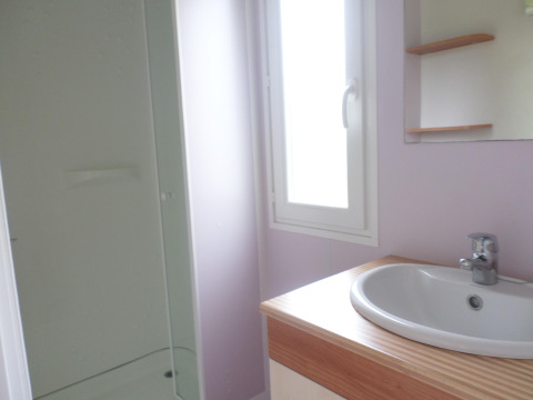 Bagno luminoso nella Stacaravan met airco al Camping Le Céou, Francia, con lavabo, specchio e doccia.