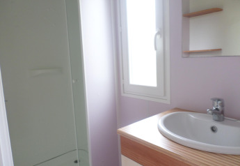 Lichte badkamer in de Stacaravan met airco op Camping Le Céou in Frankrijk met wastafel, spiegel en douche.