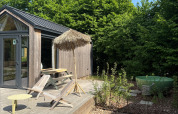 Zonnig terras bij Tiny Home MET DUTCHTUB - GENT met ligstoelen, parasol en groene hottub.