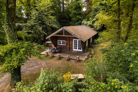 Accogliente baita in legno 'Huys van de Boswachter' con vasca idromassaggio, immersa nella foresta verde.