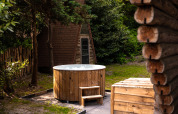 Houten buitenspa bij Huys van de Boswachter lodge op Sandberghe, Nederland, omringd door groen.