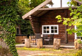 Lodge 'Huys van de Boswachter' met bubbelbad bij Sandberghe in Nederland, omgeven door bomen en natuur.