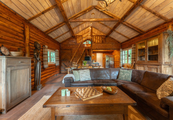 Knusse woonkamer in houten lodge 'Huys van de Boswachter' te Sandberghe, Nederland, met rustieke inrichting.