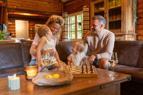 Familie genießt gemütliche Zeit in einer Blockhütte im Huys van de Boswachter mit Whirlpool in Sandberghe, Niederlande.