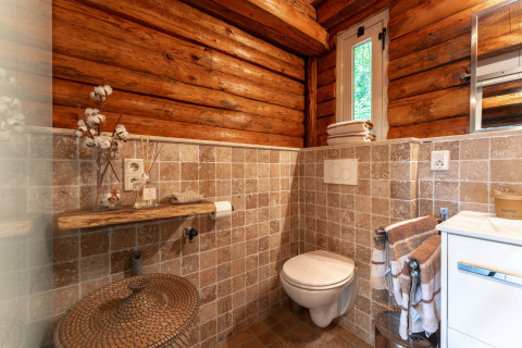 Badezimmer einer Blockhütte im Sandberghe, Niederlande, mit Holzwänden, Fliesen und gemütlicher Dekoration.