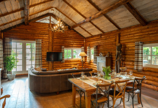 Cozy log cabin interior at Huys van de Boswachter with dining table and lounge area at Sandberghe, Netherlands.