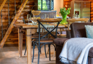 Knusse eetruimte met houten tafel en bloemen in Huys van de Boswachter, Sandberghe, Nederland.