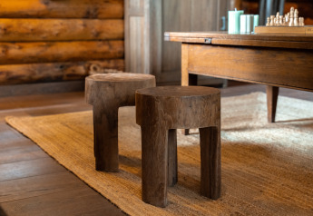 Twee houten krukken op een vloerkleed in de sfeervolle lodge 'Huys van de Boswachter' in Sandberghe.