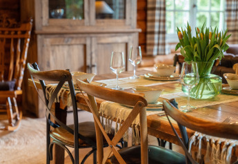 Rustieke eettafel in Huys van de Boswachter, Sandberghe, gedekt met tulpen en stijlvolle glaswerk.