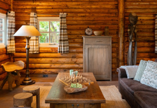 Cozy log cabin interior of Huys van de Boswachter with rustic furniture, chess set, and wooden decor in Sandberghe.