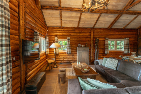 Gezellige houten lodge met rustieke stijl, bruine zetel en grote ramen in 'Huys van de Boswachter', Sandberghe.