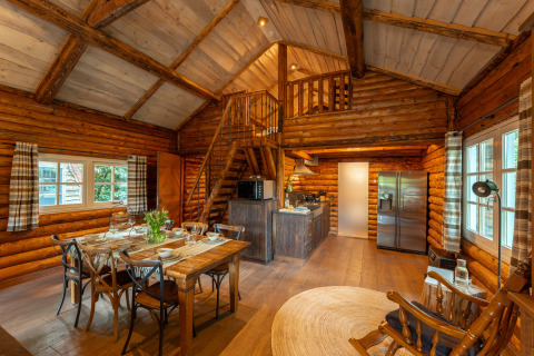 Gemütliches Blockhaus-Interieur mit Essbereich, Küche und Galerie im Sandberghe, Niederlande.