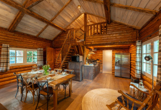Gezellig houten lodge-interieur met eetruimte, keuken en vide in Sandberghe, Nederland.