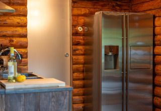 Cocina de cabaña de troncos con frigorífico y vino en Huys van de Boswachter, Sandberghe, Países Bajos.