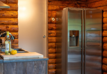 Cocina de cabaña de troncos con frigorífico y vino en Huys van de Boswachter, Sandberghe, Países Bajos.