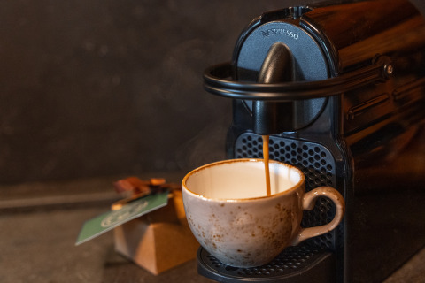 Eine Tasse wird mit frischem Kaffee aus einer Nespresso-Maschine in der Lodge 'Huys van de Boswachter' gefüllt.