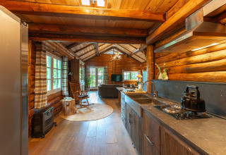 Interior of a rustic log cabin featuring a modern kitchen and cozy lounge at Huys van de Boswachter, Sandberghe.