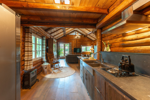 Interieur van een rustieke houten lodge met moderne keuken in Huys van de Boswachter bij Sandberghe.