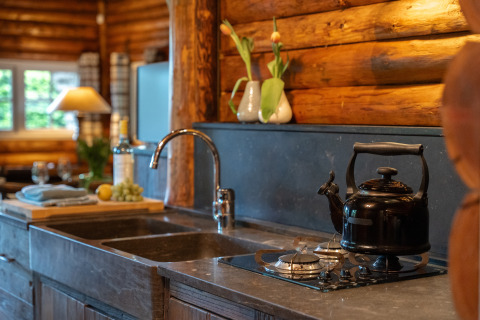 Acogedora cocina de madera en Huys van de Boswachter con tetera y flores en Sandberghe, Países Bajos.