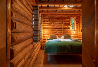 Cozy bedroom with wooden log walls at Huys van de Boswachter lodge, Sandberghe, Netherlands, rustic decor.
