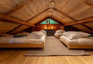 Cozy attic room with four single beds beneath rustic wooden beams at Huys van de Boswachter, Sandberghe.