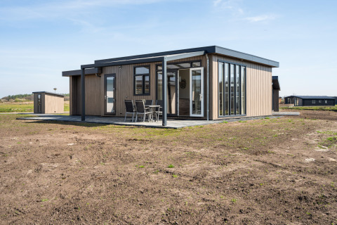 Moderne lodge met grote ramen en terras in Zandduin Deluxe, De Tien Heugten, Nederland.