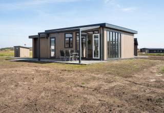 Moderne lodge met grote ramen en terras in Zandduin Deluxe, De Tien Heugten, Nederland.